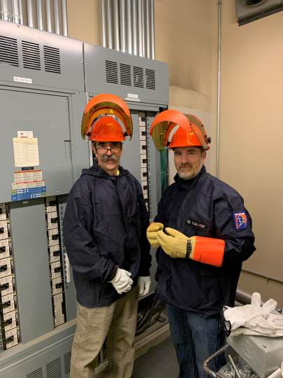 Two mechanical engineers standing in front of electrical equipment
